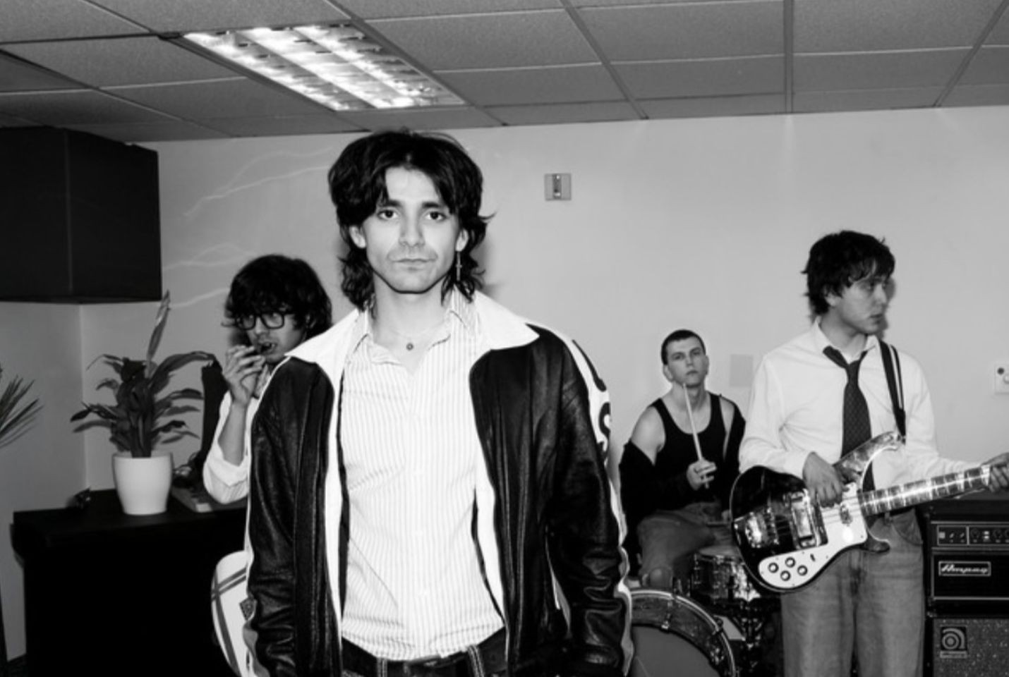 four men stand in a band practice room